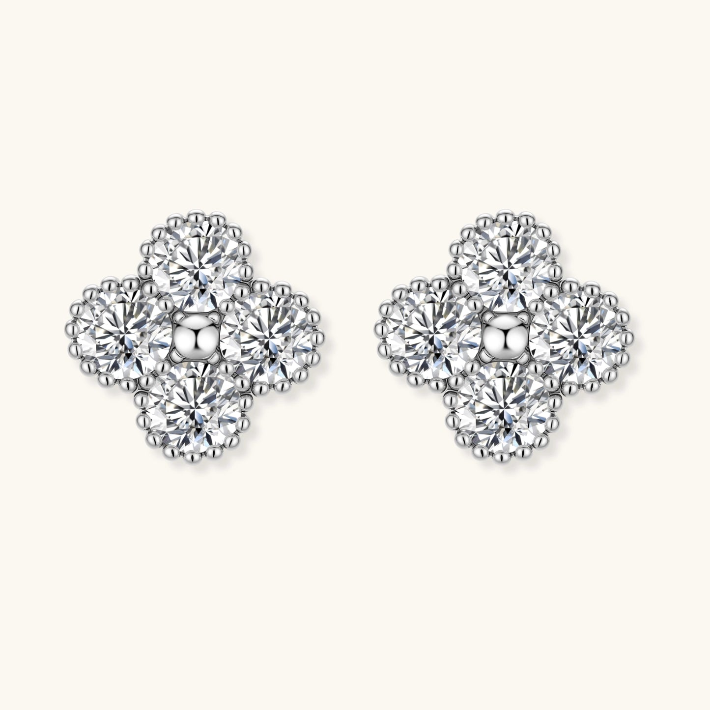 Dainty sterling silver quatrefoil stud earrings with four brilliant moissanite stones and center accent on white background.